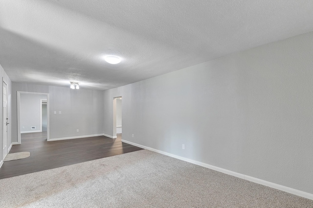 empty room featuring a textured ceiling and dark carpet