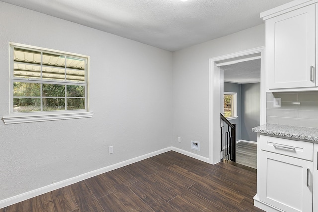 interior space featuring white cabinetry, dark hardwood / wood-style flooring, light stone countertops, and a textured ceiling