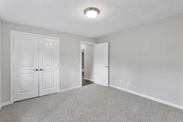 unfurnished bedroom with a textured ceiling, carpet floors, and a closet