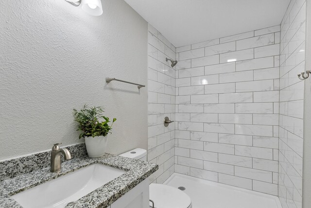 bathroom featuring vanity, toilet, and a tile shower