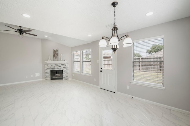 unfurnished living room with a tile fireplace, a textured ceiling, ceiling fan with notable chandelier, and lofted ceiling