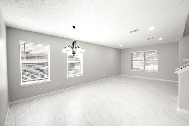 empty room featuring a textured ceiling and a notable chandelier