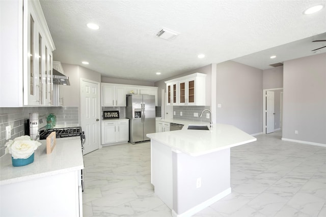 kitchen featuring kitchen peninsula, appliances with stainless steel finishes, backsplash, sink, and white cabinets