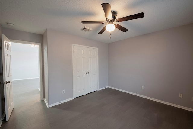 unfurnished bedroom featuring a textured ceiling, ceiling fan, dark wood-type flooring, and a closet