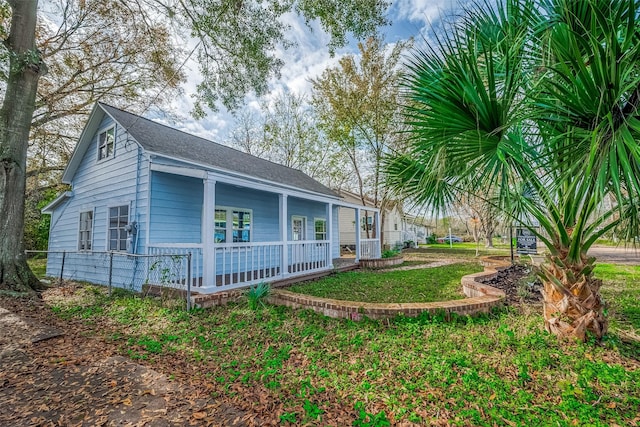 view of home's exterior with covered porch and a lawn