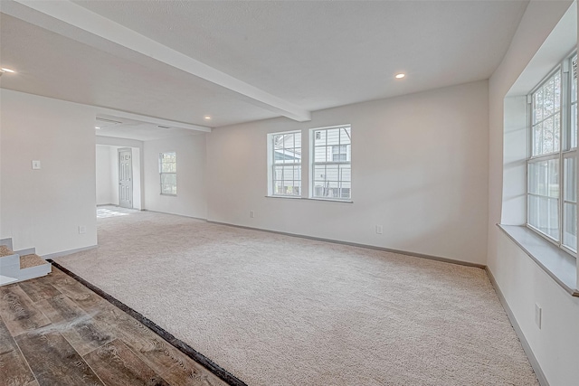 carpeted empty room with beam ceiling