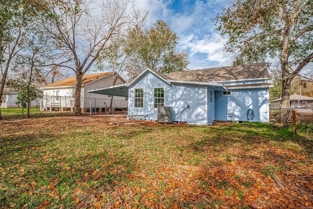 rear view of house with a carport, a yard, and central AC