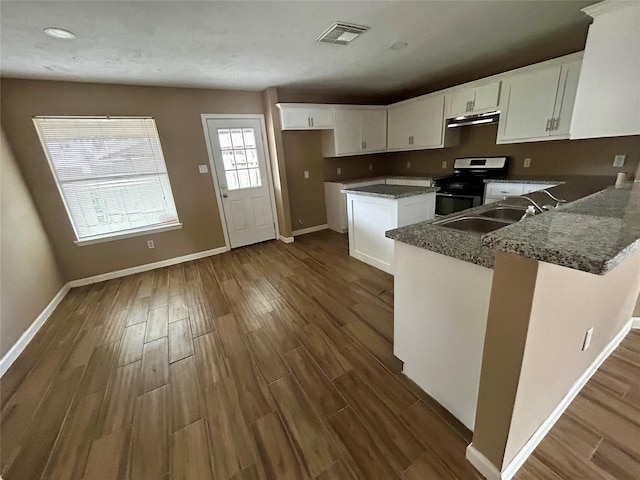 kitchen with white cabinetry, sink, stainless steel range, and dark stone counters