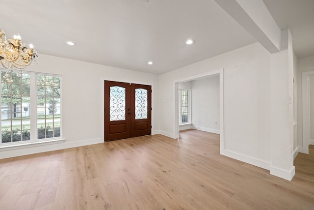 entrance foyer featuring a chandelier, french doors, and light hardwood / wood-style floors