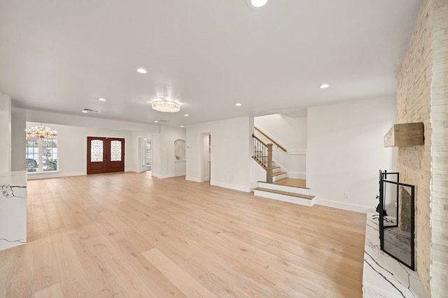 unfurnished living room with french doors, light wood-type flooring, and a stone fireplace