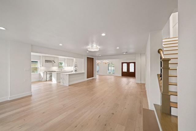 unfurnished living room with a chandelier, french doors, and light hardwood / wood-style flooring