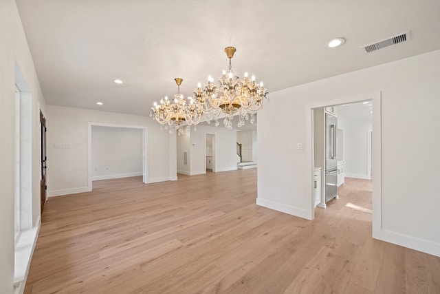 unfurnished dining area featuring light wood-type flooring and a notable chandelier