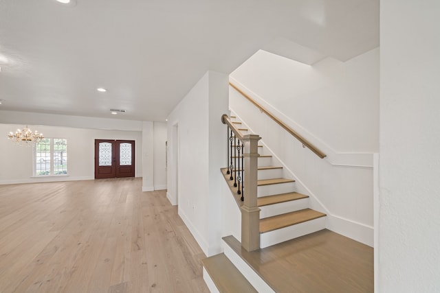 interior space featuring french doors, light hardwood / wood-style flooring, and an inviting chandelier