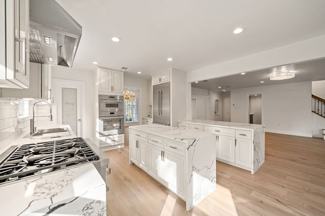 kitchen with light stone counters, extractor fan, sink, a center island, and white cabinetry