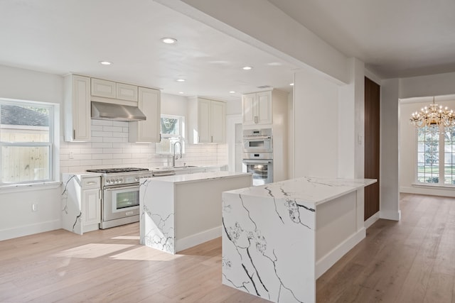 kitchen with a center island, sink, light stone countertops, range hood, and stainless steel appliances