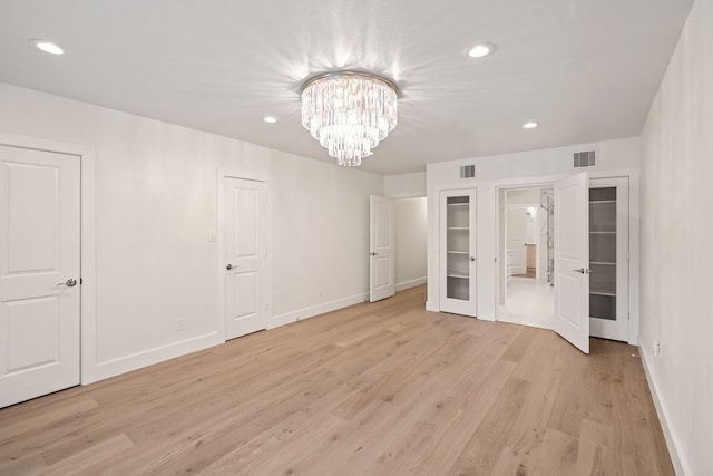 unfurnished bedroom featuring light wood-type flooring and a chandelier