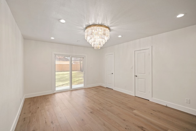 empty room with light hardwood / wood-style flooring and a chandelier