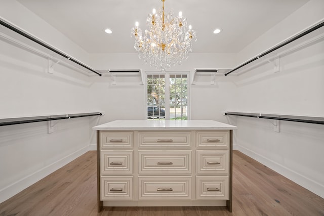 spacious closet featuring light hardwood / wood-style floors and a notable chandelier