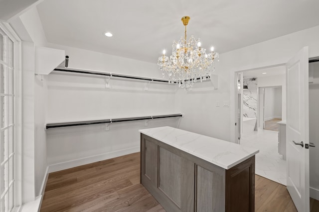 spacious closet with light hardwood / wood-style flooring and a notable chandelier