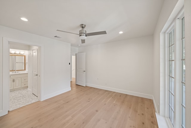 unfurnished bedroom featuring ceiling fan, light hardwood / wood-style floors, connected bathroom, and multiple windows