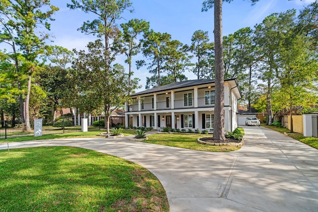 view of front facade with a porch, a balcony, and a front lawn