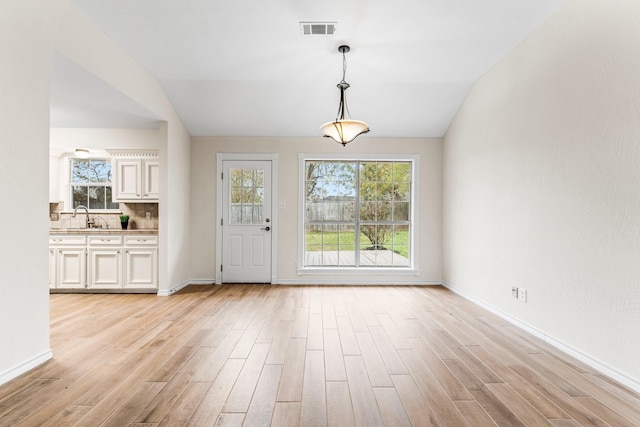 foyer featuring sink, light hardwood / wood-style floors, and lofted ceiling