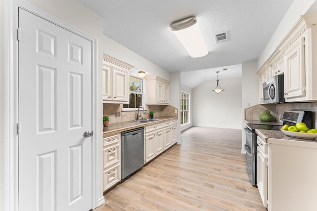 kitchen with sink, hanging light fixtures, stainless steel appliances, backsplash, and vaulted ceiling