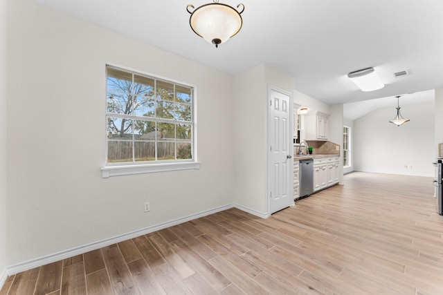 kitchen featuring white cabinets, decorative light fixtures, light hardwood / wood-style floors, and stainless steel dishwasher