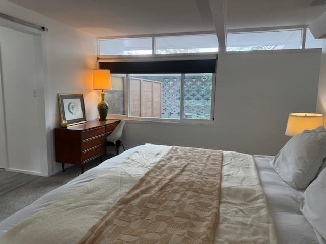 carpeted bedroom with beam ceiling