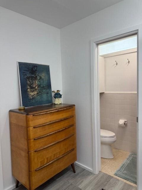 bathroom featuring hardwood / wood-style flooring, toilet, and tile walls