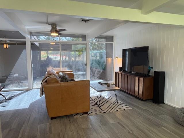 living room featuring beamed ceiling, hardwood / wood-style floors, and ceiling fan