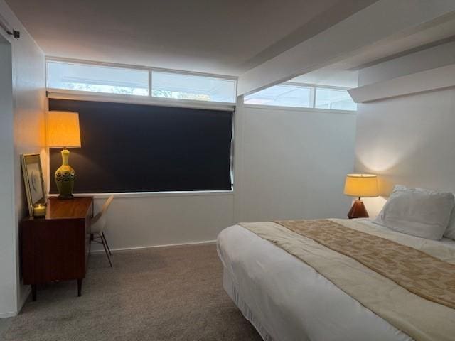 bedroom with dark colored carpet and beam ceiling