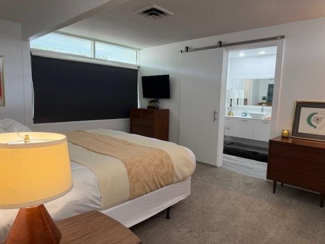 carpeted bedroom with connected bathroom, sink, and a barn door