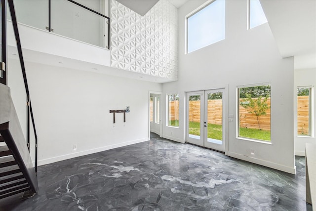 unfurnished living room featuring a towering ceiling and french doors