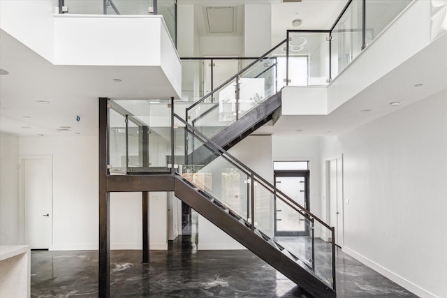 stairs featuring a towering ceiling and concrete floors