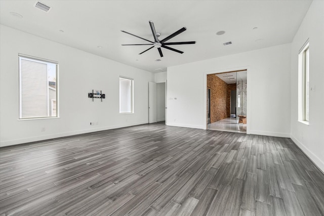 unfurnished living room with plenty of natural light, ceiling fan, and dark wood-type flooring