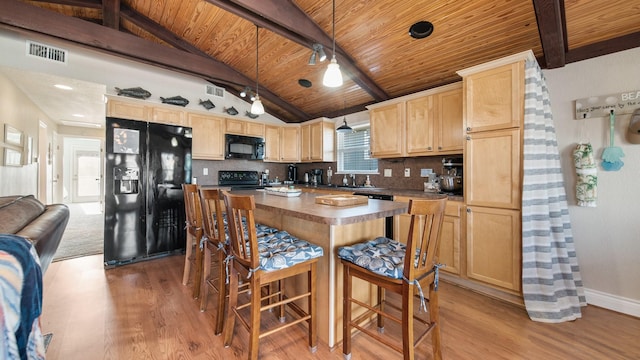 kitchen with lofted ceiling with beams, pendant lighting, light brown cabinetry, black appliances, and light wood-type flooring