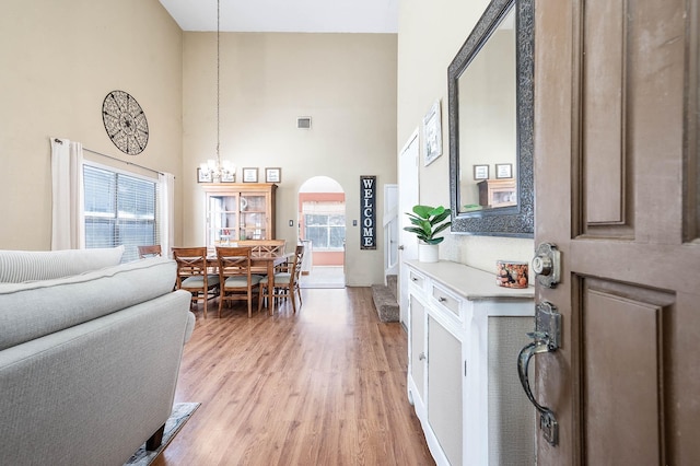 interior space with a chandelier, a high ceiling, light hardwood / wood-style floors, and plenty of natural light