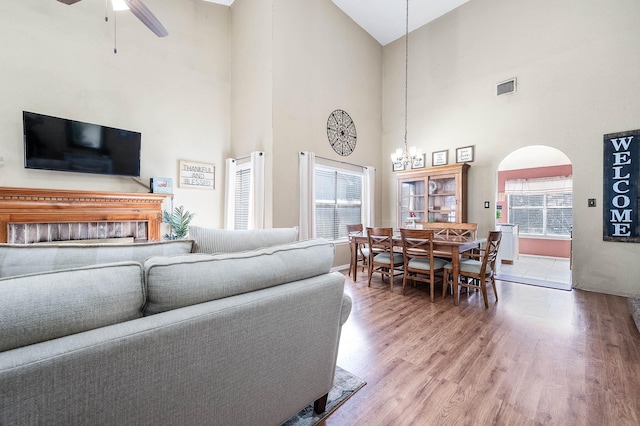 living room featuring hardwood / wood-style floors, ceiling fan with notable chandelier, high vaulted ceiling, and a healthy amount of sunlight