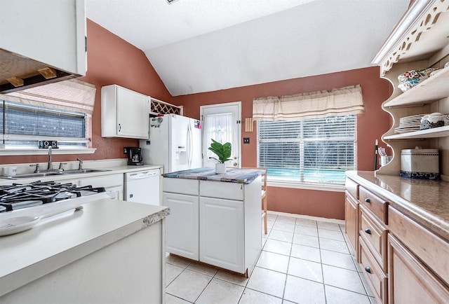 kitchen featuring white cabinets, white appliances, lofted ceiling, and light tile patterned floors