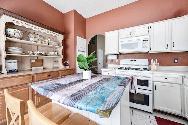 kitchen featuring light tile patterned floors, white appliances, a textured ceiling, and white cabinetry