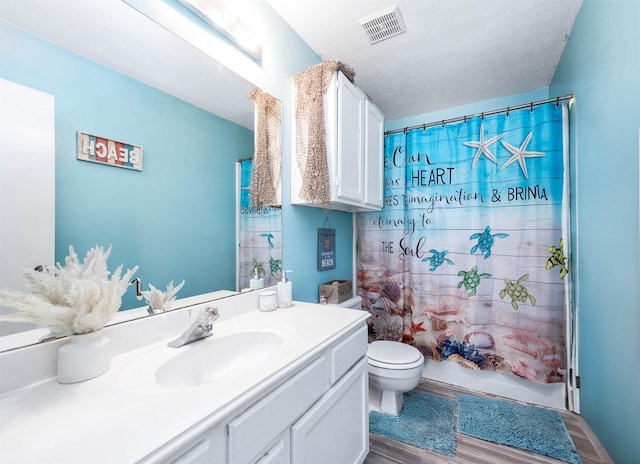 full bathroom with a textured ceiling, toilet, shower / tub combo with curtain, vanity, and hardwood / wood-style flooring