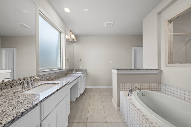 bathroom with tile patterned floors, vanity, and a relaxing tiled tub