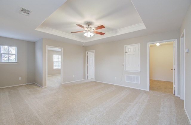 unfurnished room featuring light colored carpet, a raised ceiling, and ceiling fan