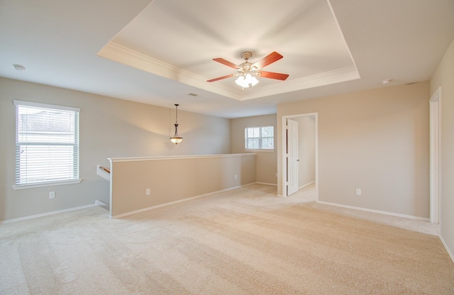 carpeted empty room featuring ceiling fan, ornamental molding, and a tray ceiling