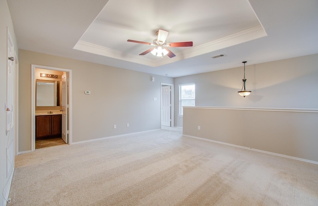 empty room featuring a tray ceiling, crown molding, and light colored carpet