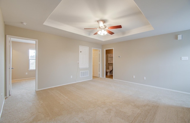 unfurnished room featuring a tray ceiling, crown molding, ceiling fan, and light colored carpet