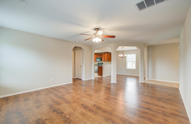 unfurnished living room featuring ceiling fan with notable chandelier and hardwood / wood-style flooring