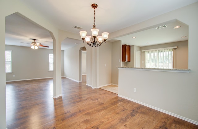 spare room featuring ceiling fan with notable chandelier and dark hardwood / wood-style floors