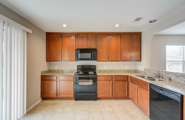 kitchen featuring light stone counters, sink, light tile patterned floors, and black appliances